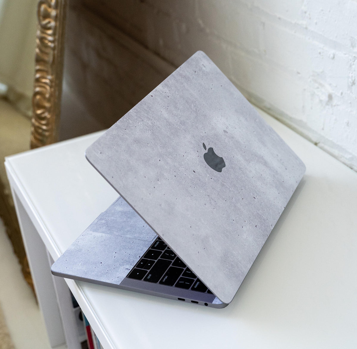 MacBook Air or Pro laptop featuring a textured grey concrete-style protective skin cover.
