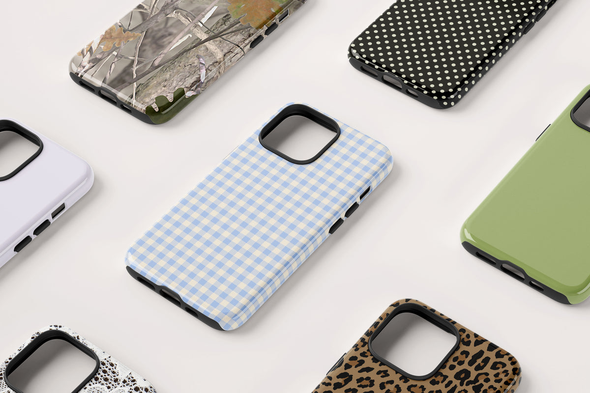 Assorted iPhone cases with various patterns including gingham, camouflage, polka dots, and leopard print on a white background.