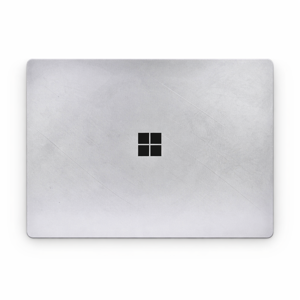 Top-down view of a silver laptop lid with a brushed metal texture and a black Microsoft logo in the center.